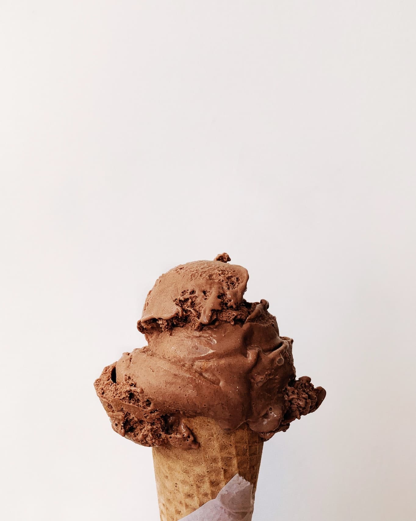 A scoop of chocolate ice cream on a cone.