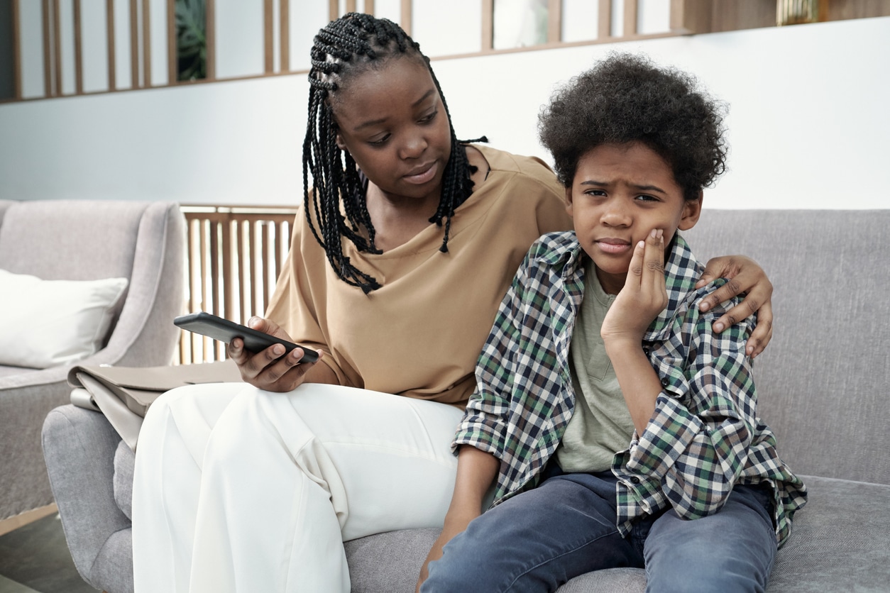Mom and kid sitting on a couch, kid experiencing tooth pain
