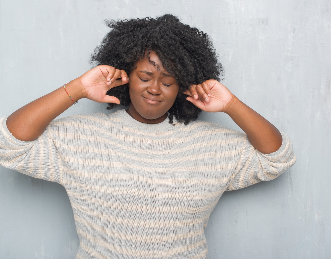 Woman plugging her ears to try and stop musical ear