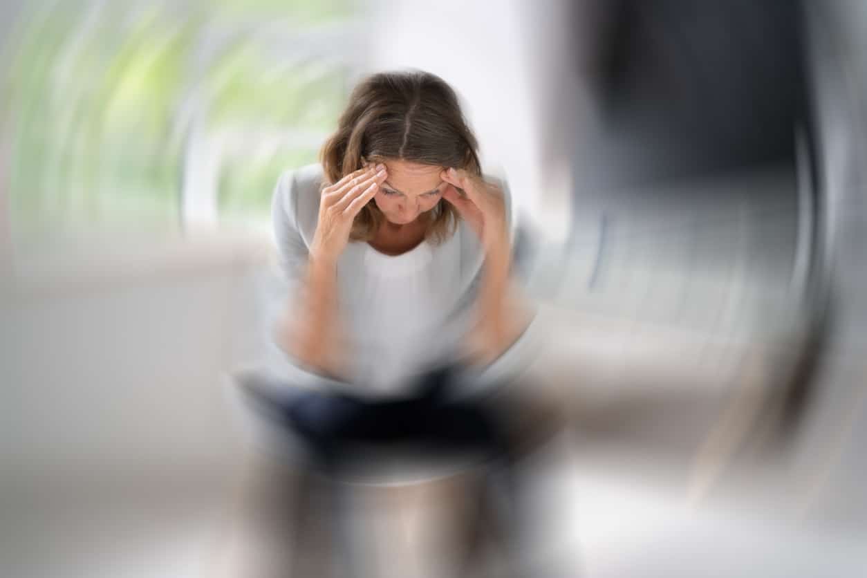 Woman with vertigo sitting down and holding her head