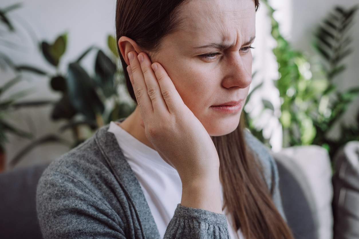 Woman with an ear infection holding her ear