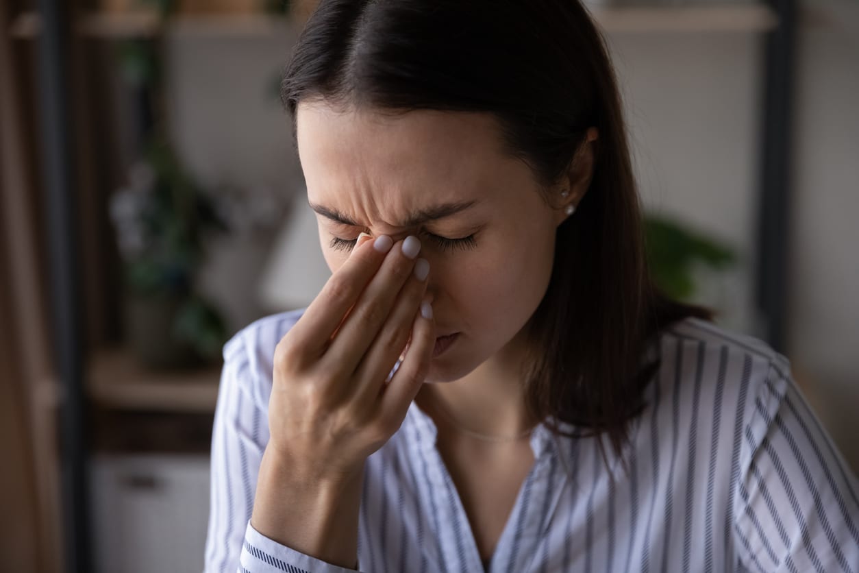 Woman with sinus pressure holding the bridge of her nose