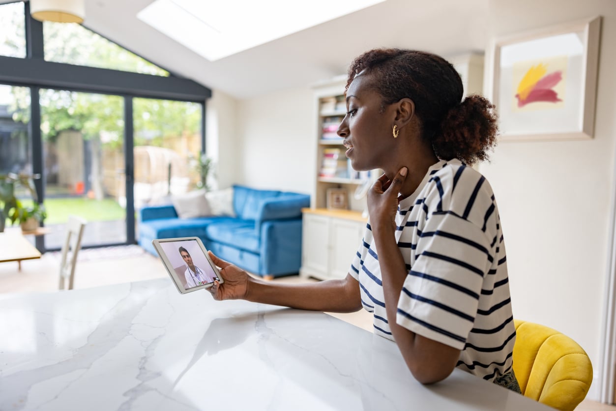 Woman at home talking to a doctor about her sore throat on a video call