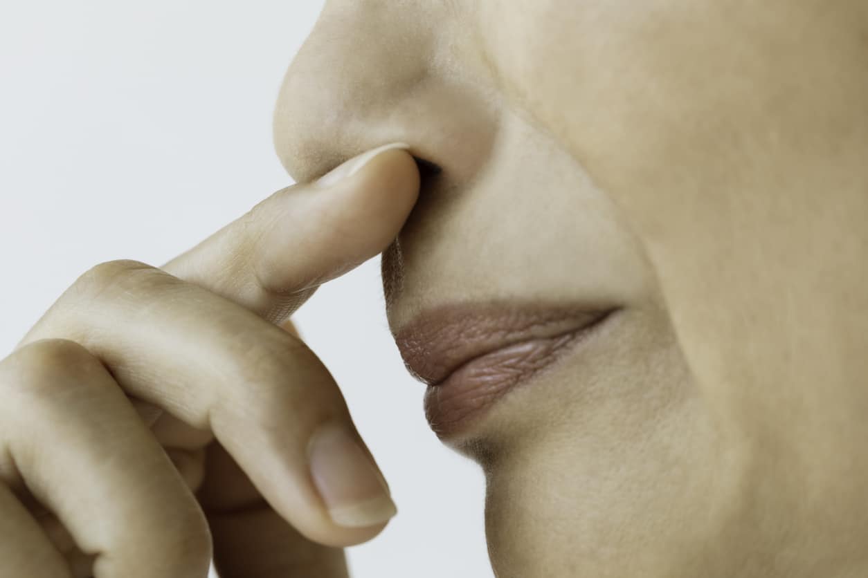 Woman holding her finger to her nose