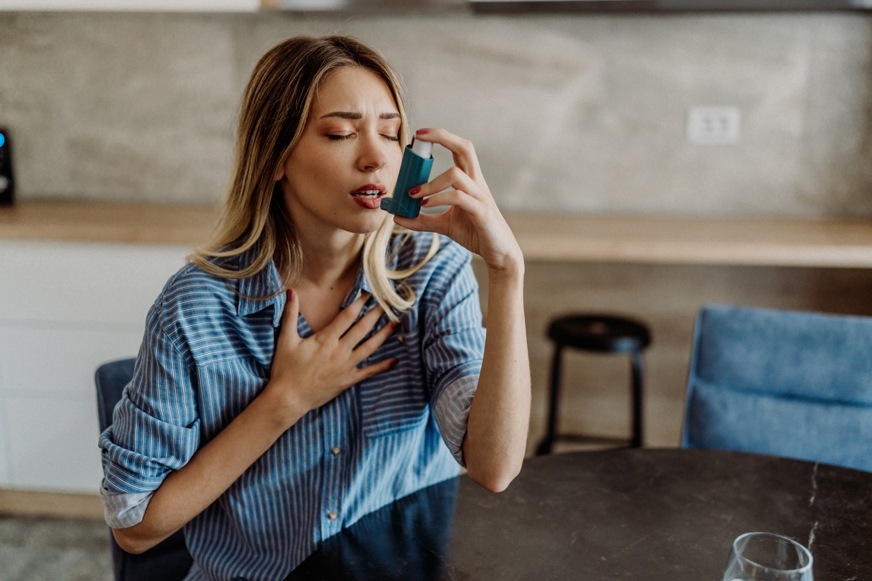Young woman with asthma using her inhaler
