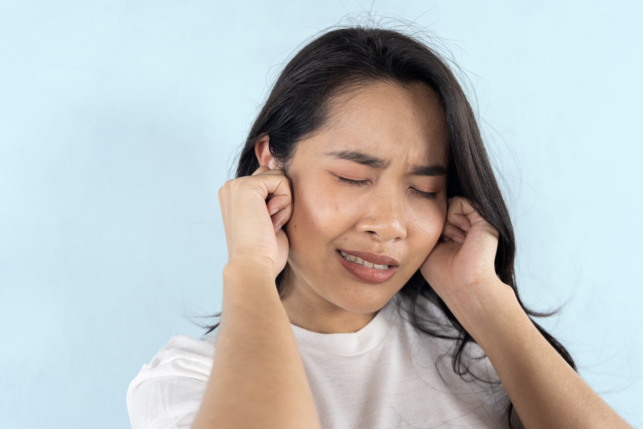 Woman on blue background holding her ears