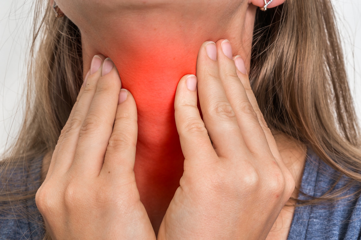 Woman with throat sore is holding her aching throat