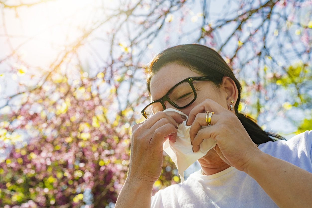 Woman with seasonal allergy using paper tissue to blow her nose