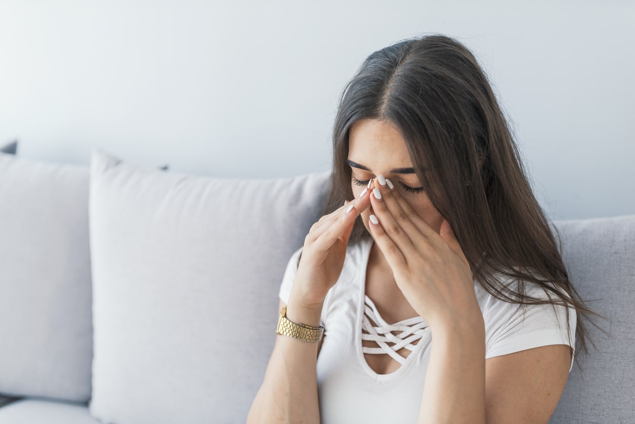 Woman holding her nose and head because sinus pain
