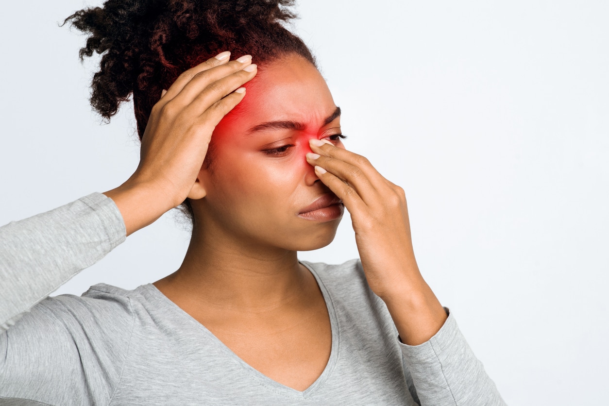 Woman with sinusitis holding her red nose and forehead