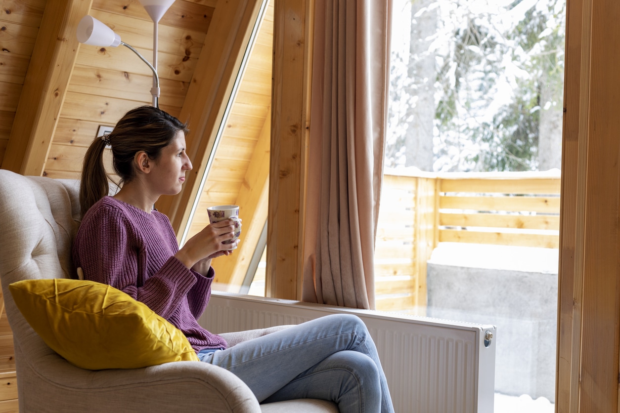 Woman with a hearing aid looking out a snowy window